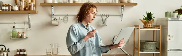 A young man interacts with a laptop, showing enthusiasm in a cozy home environment. — Stock Photo