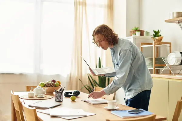 Un joven estudia una receta en una mesa de madera, rodeada de ingredientes frescos. - foto de stock