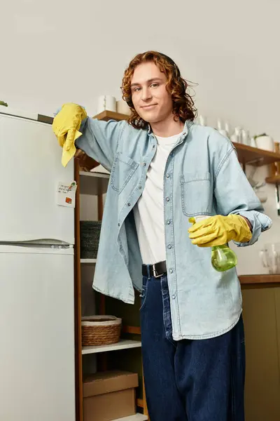 Handsome young man in casual attire stands confidently at home, ready for cleaning tasks. — стоковое фото