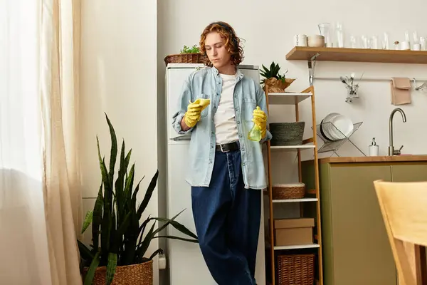 Handsome young man in yellow gloves tidying up his stylish kitchen space with care. — Stock Photo