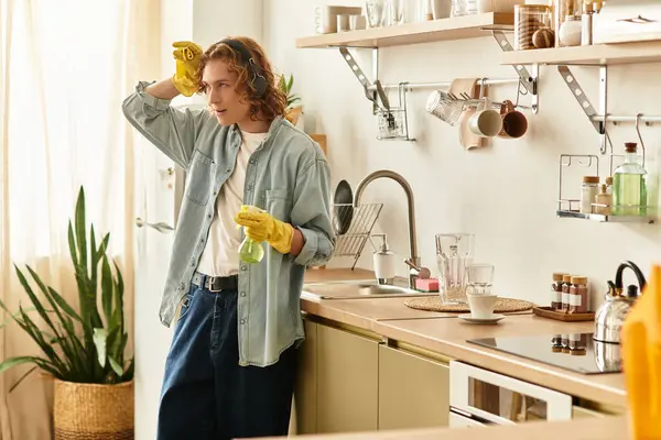 Handsome young man stands in his elegant kitchen, thoughtfully holding a drink and smiling. — Stock Photo