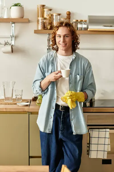 A young and handsome man stands in his stylish kitchen, sipping coffee and feeling at home. — Stock Photo