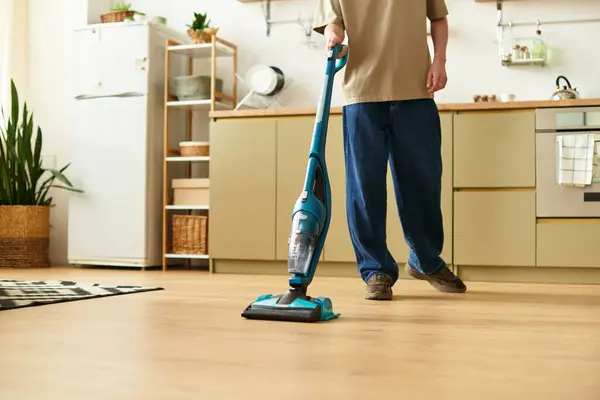 Un joven arregla su elegante casa, utilizando una aspiradora para eliminar el polvo y la suciedad. - foto de stock