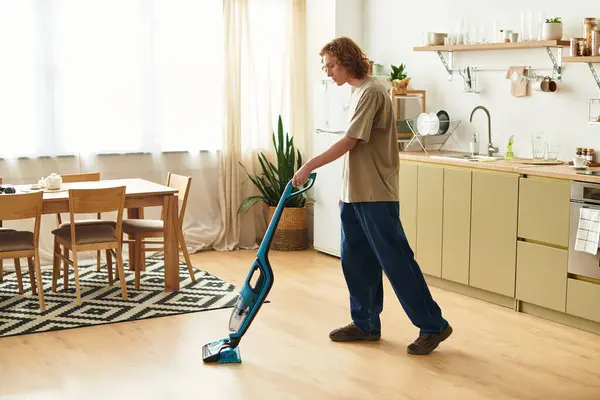 Handsome young man enjoys tidying up his stylish home while absorbing afternoon sunlight. — Stock Photo
