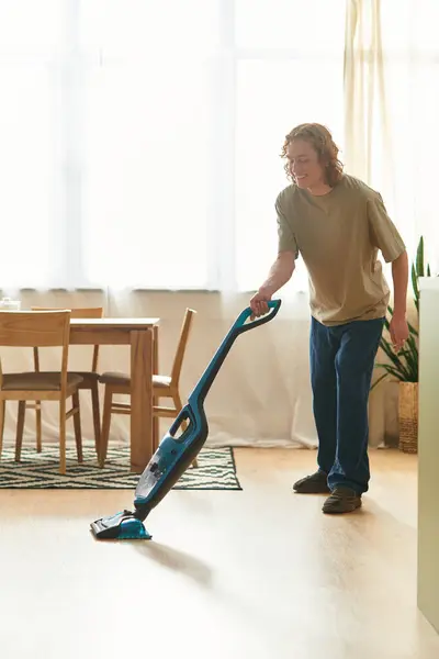 Charming young man happily vacuuming the floor in his inviting living space during the day — Stock Photo