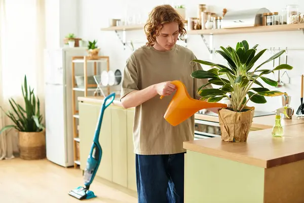 Bright afternoon finds a young man nurturing a houseplant in his modern kitchen space. — Stock Photo