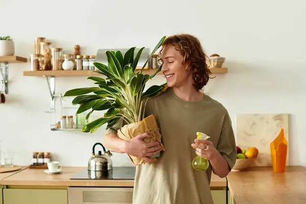 A handsome young man joyfully tends to his indoor plants in a sunny kitchen atmosphere. — Stock Photo