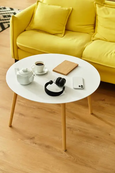 Mesa de centro estética moderna blanca con teléfono inteligente, auriculares, taza y hervidor de agua en casa acogedora. — Stock Photo