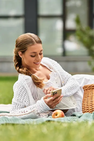 Relaxing on a picnic blanket in a lush park, a young woman savors her time outdoors. — Stock Photo