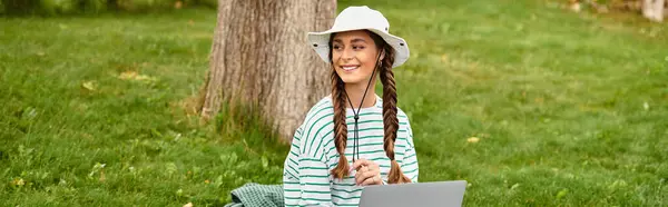 Una joven alegre se toma un descanso durante su picnic, felizmente rodeada de vegetación. - foto de stock