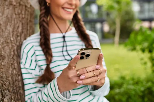 A young beautiful woman enjoys a delightful picnic in the park while interacting with her phone. — Stock Photo