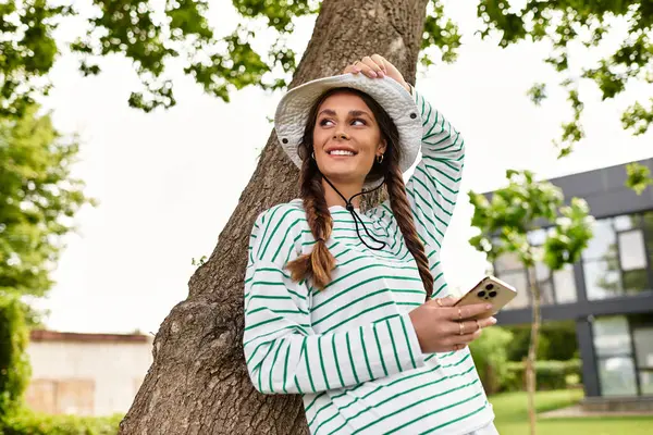 A beautiful woman relaxes under a tree, enjoying a delightful picnic and taking pictures. — Stock Photo