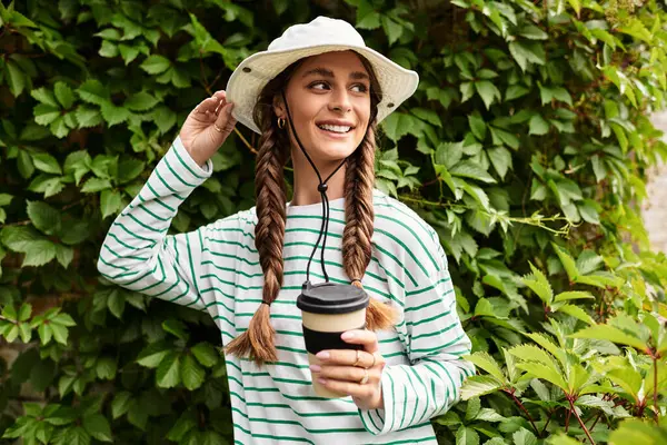 A joyful young woman with braids, wearing a hat, savoring time outdoors on a picnic in the park — Stock Photo