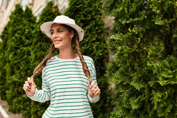 Young woman with braids smiles joyfully while having a picnic in a lush park setting — Stock Photo
