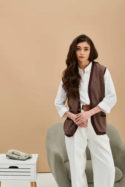 A young woman with long brown hair showcases her trendy outfit in a modern studio setting. — Stock Photo
