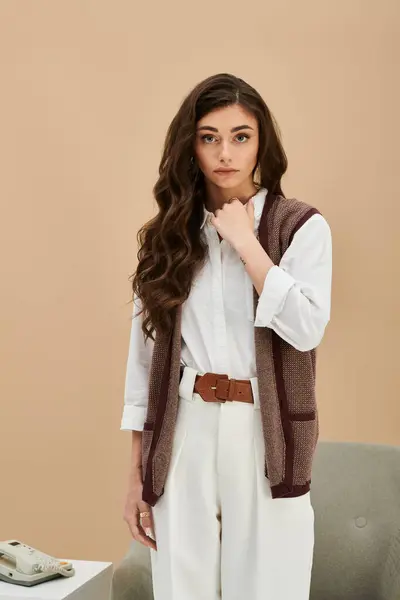 A young woman with long brown hair showcases her fashionable outfit in a modern studio setting. — Stock Photo