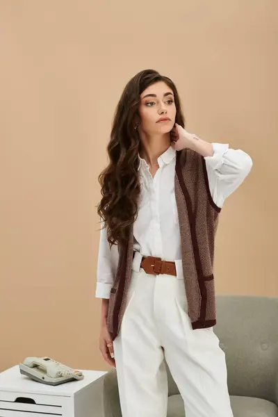 A beautiful young woman stands confidently in classic stylish attire while posing in a studio. — Stock Photo
