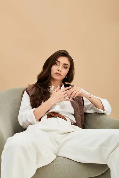 A young woman with long brown hair elegantly showcases a fashionable outfit in a modern studio. — Stock Photo