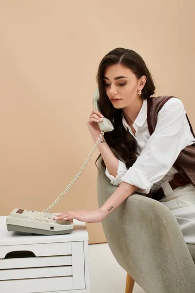 A young woman with long brown hair makes a call in trendy attire. — Stock Photo