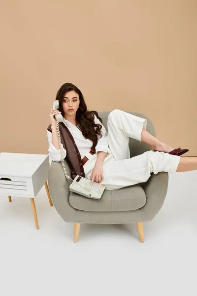 Relaxing in a stylish chair, she embodies contemporary fashion with grace and elegance. — Stock Photo