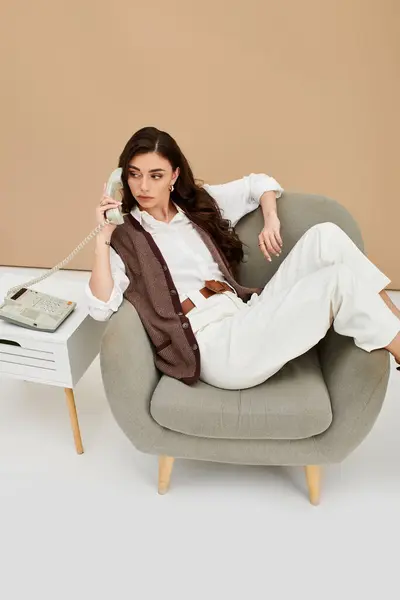 A young woman relaxes in a cozy chair while engaging in a conversation, dressed elegantly. — Stock Photo