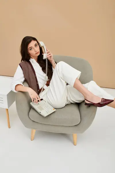A beautiful young woman with long brown hair communicates on a classic phone in a studio setting. — Stock Photo