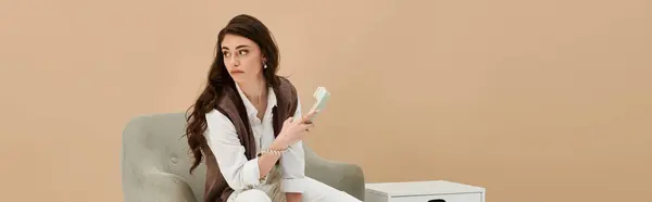 Beautiful young woman with long brown hair showcases a fashionable ensemble while seated, banner — Stock Photo