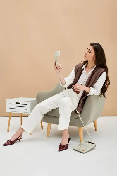 A young woman with long brown hair enjoys a call while seated in a stylish outfit. — Stock Photo