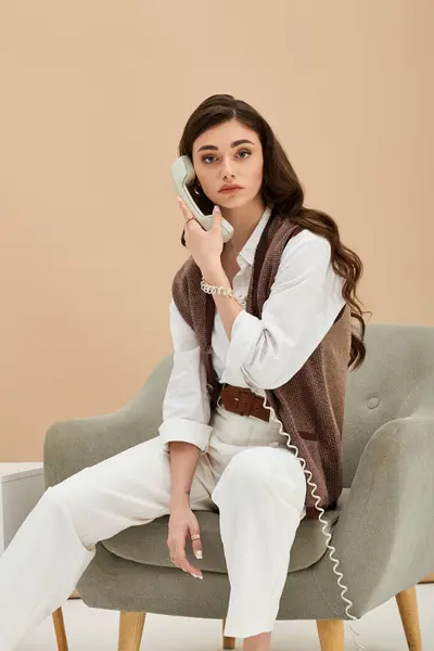 A stylish young woman with long brown hair chats on an old-fashioned phone. — Stock Photo