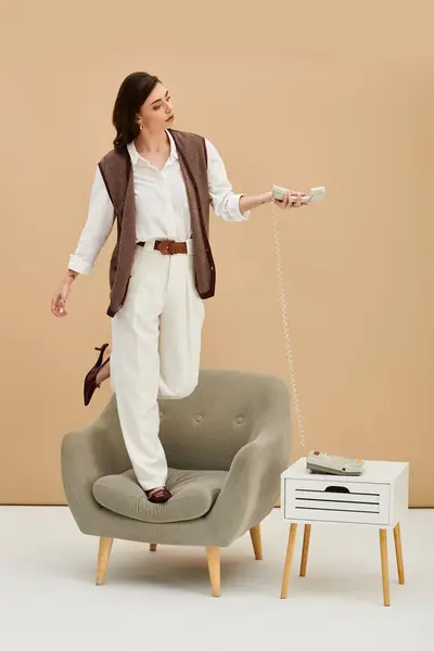 A young woman with long brown hair poses confidently on a chair in stylish attire. — Stock Photo
