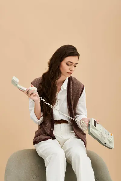 A young woman with long brown hair sits elegantly with a vintage telephone. — Stock Photo