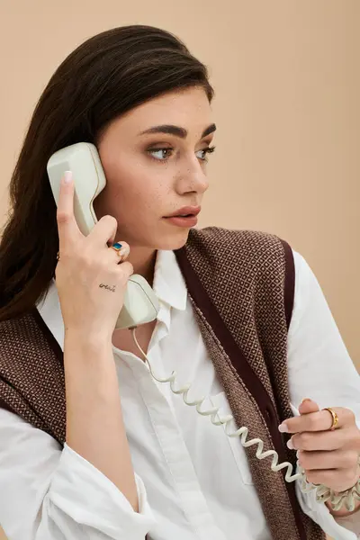 A lovely young woman with long brown hair chats on a vintage phone, showcasing modern fashion. — Stock Photo