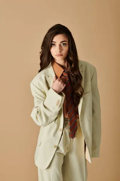 A beautiful young woman exudes confidence while wearing a chic suit with a tie in a neutral studio. — Stock Photo