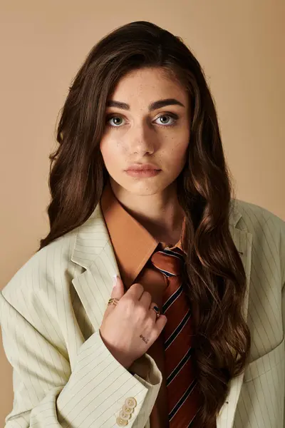 A young woman with long brown hair poses confidently in a trendy suit and tie, exuding elegance. — Stock Photo