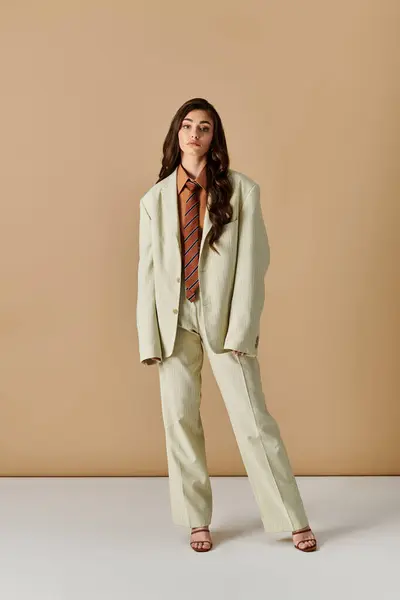 Young woman with long brown hair showcases trendy outfit with suit and tie in studio setting. — Stock Photo