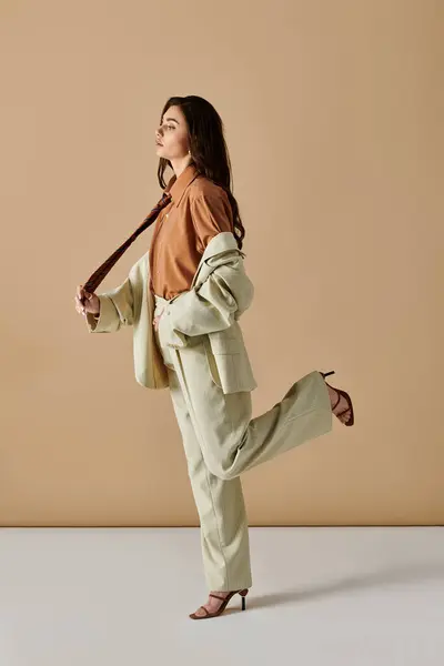 In a modern studio, a beautiful young woman showcases her fashionable attire with elegance. — Stock Photo