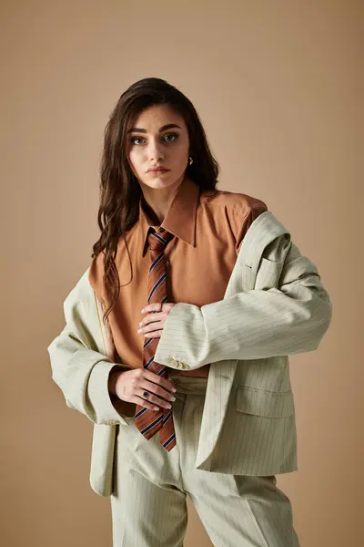 A beautiful young woman poses gracefully in a fashionable suit with a tie, exuding confidence. — Stock Photo