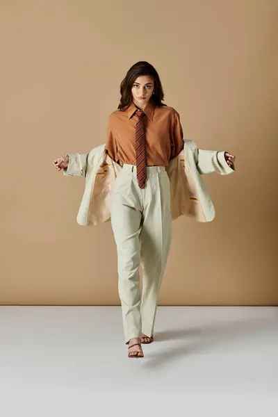 Young woman with long brown hair poses in a trendy suit, exuding elegance and poise. — Stock Photo