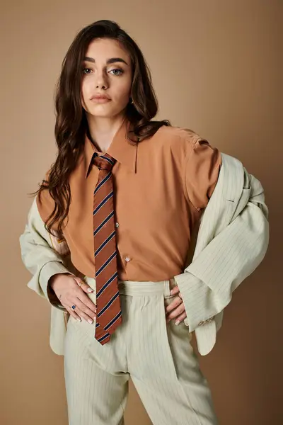Young woman with long brown hair flaunts her chic outfit in a studio, radiating confidence. — Stock Photo