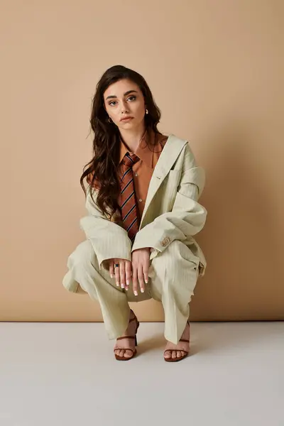 A young woman with long brown hair poses elegantly in a stylish suit and tie. — Stock Photo