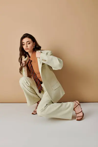 A confident young woman crouches in a fashionable outfit, showcasing her unique style in a studio. — Stock Photo