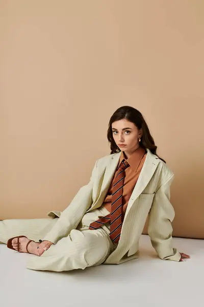 A fashionable young woman exudes confidence in her sleek suit and tie while posing in a studio. — Stock Photo