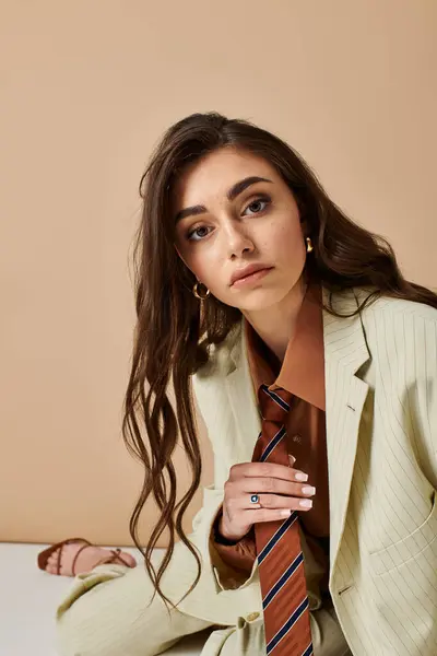 A beautiful young woman showcases her fashion sense in a stylish suit with a tie, posing gracefully. — Stock Photo