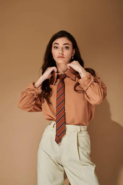 Confident young woman showcases a fashionable outfit with long brown hair in a studio. — Stock Photo