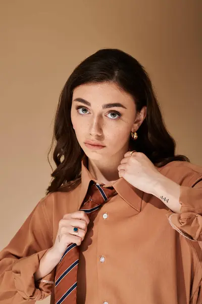 This striking young woman in a stylish suit gracefully adjusts her tie in a cozy studio. — Stock Photo