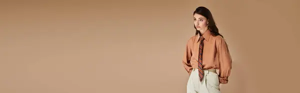 A beautiful young woman with long brown hair showcases a trendy outfit and tie in a studio, banner — Stock Photo