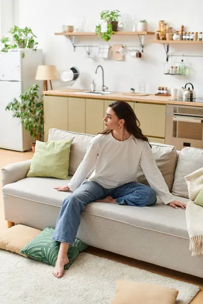 A beautiful young woman with brown hair relaxes in her casual clothes at home, enjoying her space. — Stock Photo