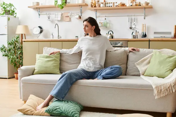 A beautiful woman with brown hair enjoys a peaceful moment in her cozy apartment, dressed casually. — Stock Photo
