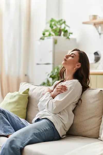 A young woman with brown hair enjoys a peaceful moment while resting in her cozy apartment. — Stock Photo