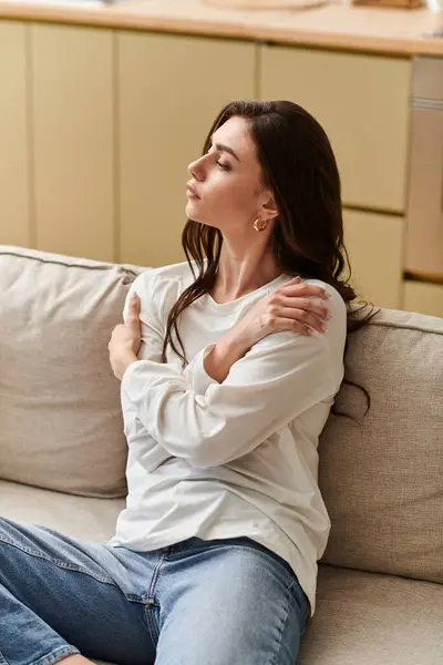 A young woman with brown hair is resting on a sofa in her cozy apartment, embracing tranquility. — Stock Photo